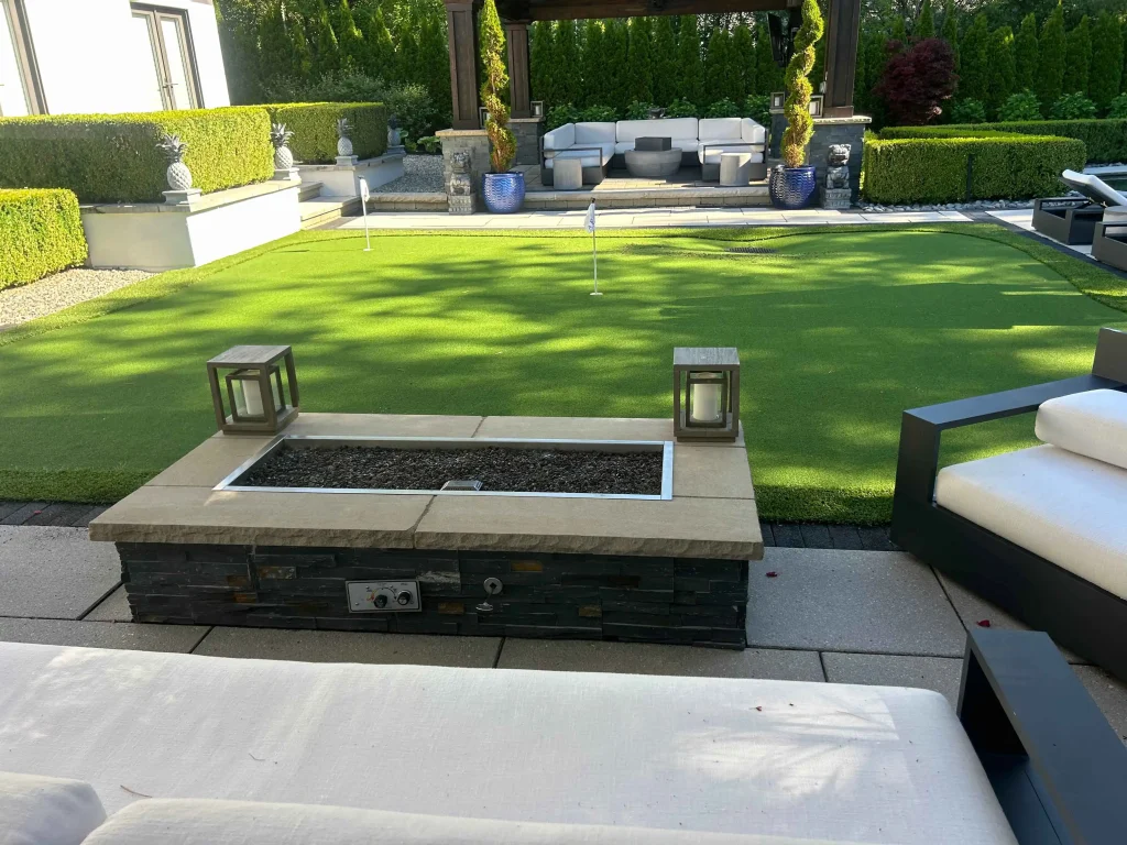 backyard patio with dark pavers, fire feature, and landscaped outdoor area