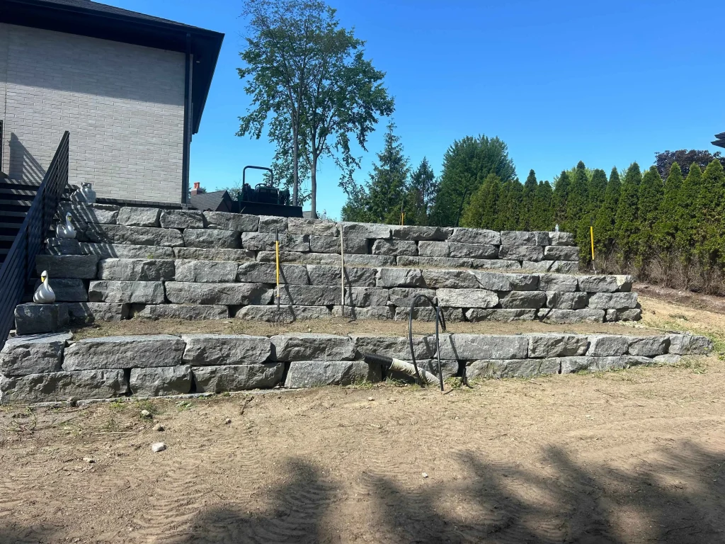 Segmental retaining wall construction with concrete blocks during landscape installation in Bridge View Dr, Bloomfield Hills, MI, USA
